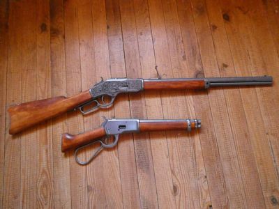deux armes posées l'une à côté de l'autre sur un plancher en bois