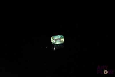 a close up of a green emerald stone on a black surface