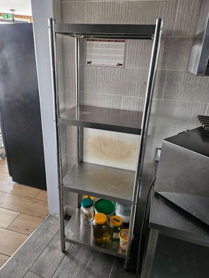 une étagère métallique dans une cuisine, sur laquelle sont posées des casseroles et des poêles
