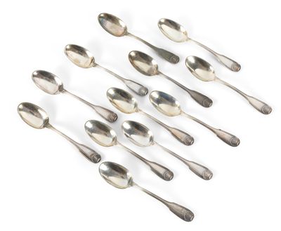 six cuillères en argent sont disposées en ligne sur une surface blanche