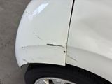the front of a white car with a dent in it ' s side