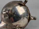 an antique silver plated teapot with a bird on top of it