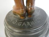 a bronze statue of a woman ' s legs on top of a bell