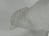 a glass bird that is sitting on a white surface