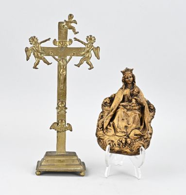 une statue représentant une femme assise sur une chaise à côté d'une croix