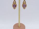 a pair of purple and gold earrings on a gold stand