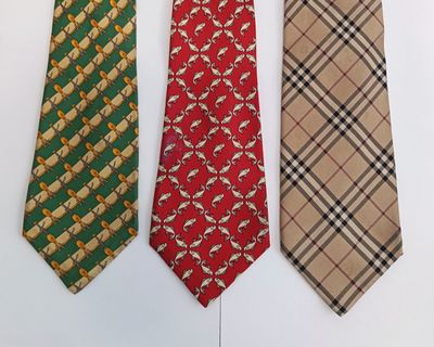 three different colored neck ties are lined up on a white surface