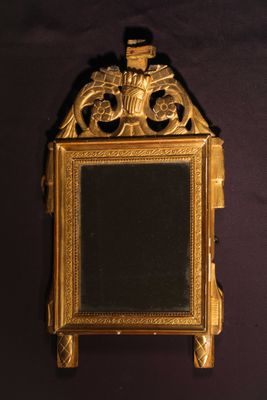 a gold mirror hanging on the wall with a black background