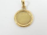 a close up of a gold pendant on a white surface