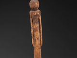 a wooden statue of a man standing on a black surface