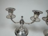 three silver candlesticks on a white table