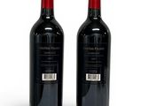 two bottles of red wine sitting next to each other on a white surface