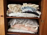 a wooden cabinet filled with lots of clothes and blankets