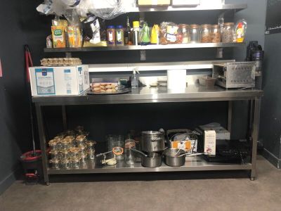 une étagère métallique sur laquelle sont posés des casseroles et des poêles