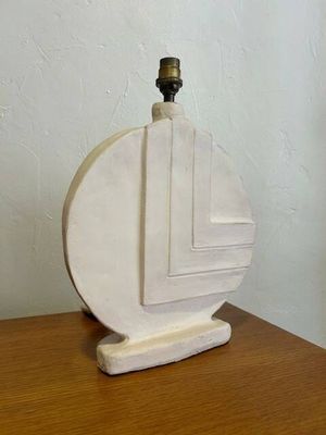 a white vase on a wooden table with a candle on it
