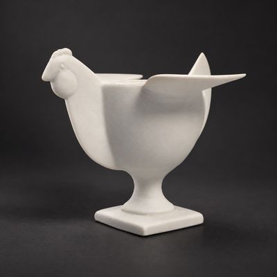 un vase blanc posé sur une table, devant un fond noir