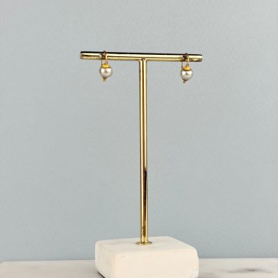 une table en marbre blanc et doré sur laquelle sont posées deux boucles d’oreilles