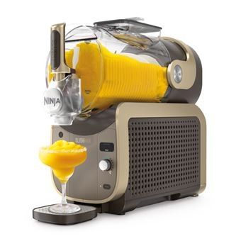 une centrifugeuse avec un verre de jus d'orange à côté