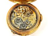 a gold pocket watch that is open on a white surface