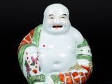 figurine en porcelaine chinoise représentant un homme souriant tenant un éventail, sur fond noir