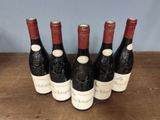 six bottles of wine are lined up on a wooden table