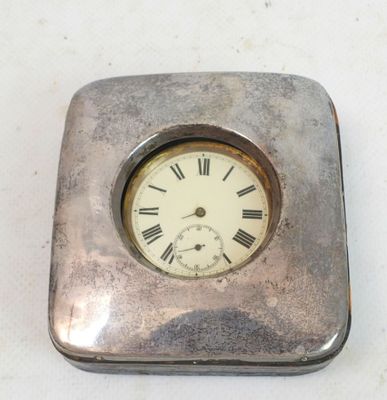 a small silver clock with roman numerals on it