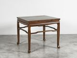 une petite table en bois avec un plateau en marbre posée sur un sol en béton