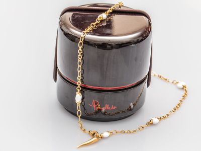 une boîte noire sur laquelle sont accrochés une chaîne en or et un collier de perles