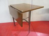 a small wooden table with a folding top on a red floor