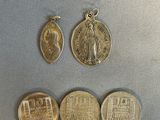 three gold coins and a silver medal on a silver surface