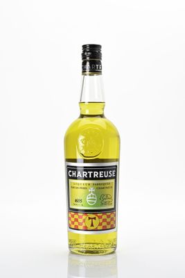 une bouteille de liqueur de citron Chartreuse posée sur une surface blanche