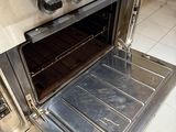 a silver oven with a metal door open on a tiled floor