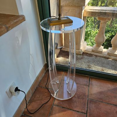 une table en verre sur laquelle est posé un livre, devant une fenêtre