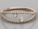 a close up view of a rose gold ring with two diamonds