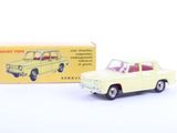 une petite voiture jaune devant une boîte de jouets posée sur une surface blanche
