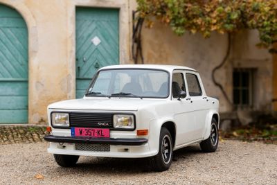 une petite voiture blanche garée devant un bâtiment