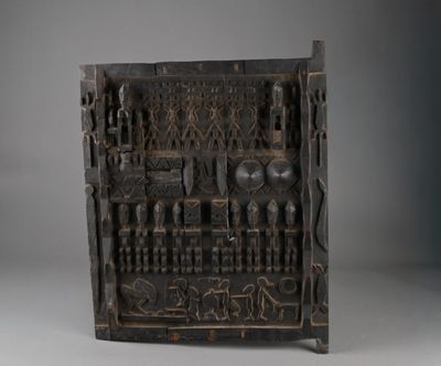 un vieux panneau en bois orné de sculptures sur une surface grise