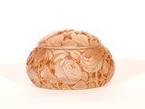 Des motifs de fleurs et de feuilles sont sculptés à la surface d'un bol