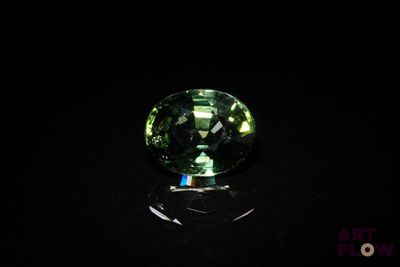 un gros plan d'une tourmaline verte posée sur une surface noire