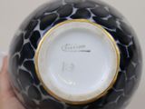 someone is holding a black and white vase with a gold rim