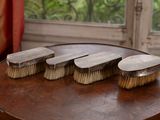 quatre pinceaux posés sur une table en bois devant une fenêtre