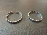 two silver hoop earrings on top of a leather surface