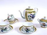 quatre tasses et soucoupes ainsi qu'une théière posées sur une table blanche