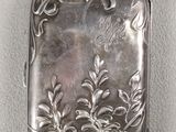 a silver cigarette case sitting on a white surface