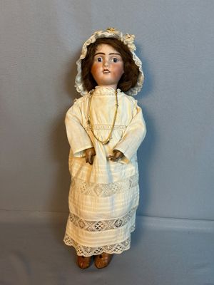 une poupée ancienne représentant une femme en robe blanche et coiffe