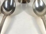 three silver spoons and a silver bowl on a white surface