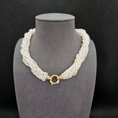un collier de perles blanches muni d'un fermoir en or, posé sur un mannequin
