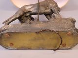 a statue of a dog on a table with a clock in the background