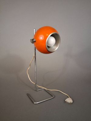 an orange lamp that is sitting on a metal stand