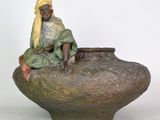 a statue of a woman sitting on top of a vase